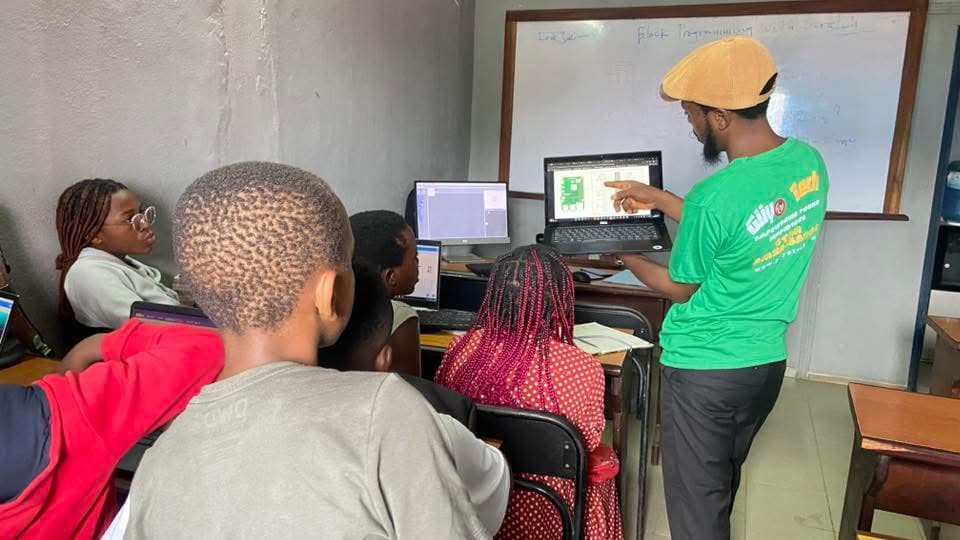 An instructor guiding students at a laptop